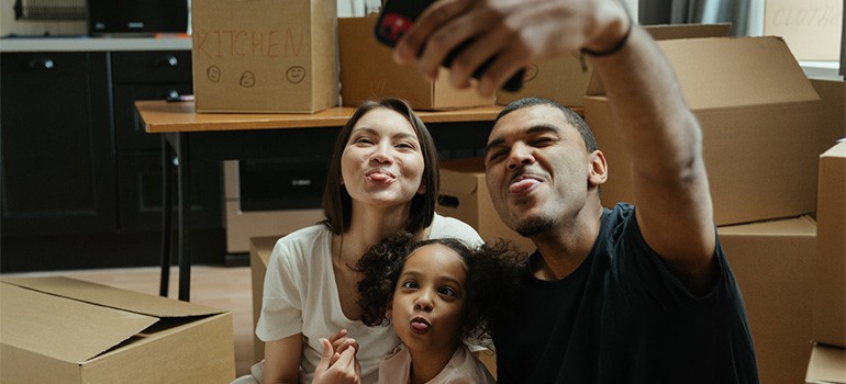 A family taking pictures with packed boxes, enjoying their move