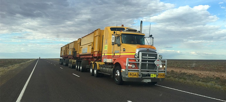 A big yellow truck on a clear road