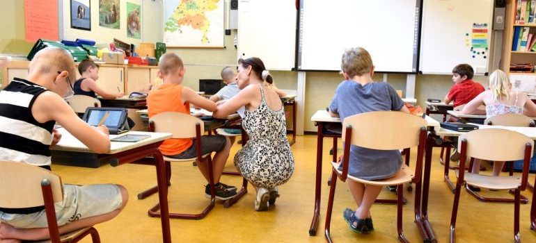 A teacher talking to a child seated behind their desk