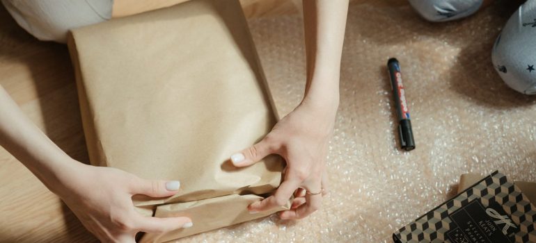 a woman wrapping an item with packing paper